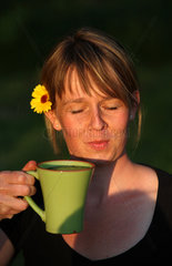 Schependorf  Deutschland  Frau mit Blume im Haar trinkt aus einer Tasse