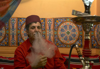 Berlin  arabischer Mann mit Fes raucht Wasserpfeife