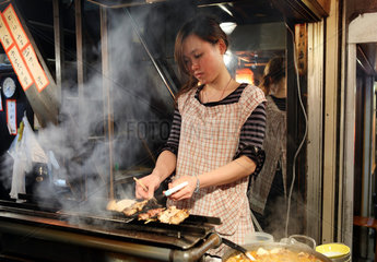 Tokio  Japan  eine Frau bereitet Fleischspiesse zu