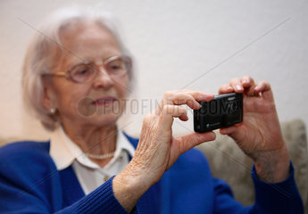 Berlin  Deutschland  eine aeltere Frau macht mit ihrem Handy ein Foto