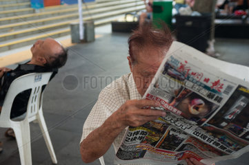 Republik Singapur  Mann liest Zeitung in Chinatown