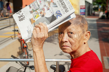 Republik Singapur  Mann mit einer Zeitung in Chinatown