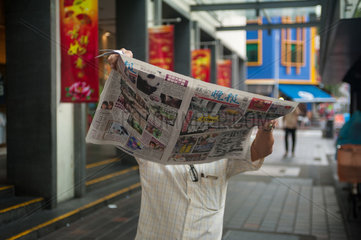 Republik Singapur  Mann liest Zeitung in Chinatown