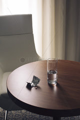 Glass of water and medication on table in hotel room