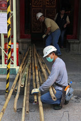Hong Kong  China  Bauarbeiter kniet vor langen Bambusstaeben