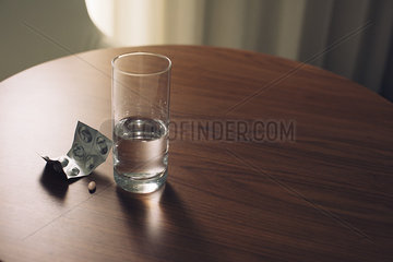 Glass of water and blister pack of medicine on table