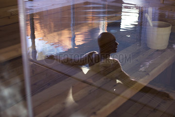 Man relaxing in swimming pool  reflected on glass door