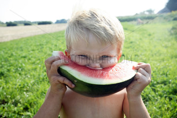 Prangendorf  Deutschland  Junge isst ein Stueck Wassermelone
