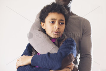 Boy leaning against father with worried expression on face