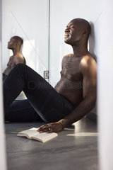 Man sitting on floor with book  eyes closed