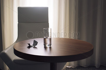 Glass of water and medication on table in hotel room
