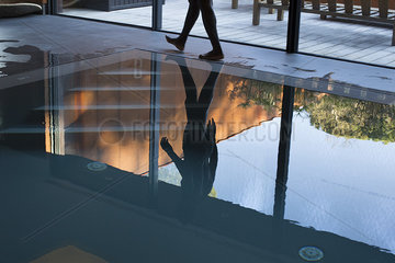 Man walking beside pool  reflected on water