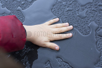 Child touching wet metallic surface