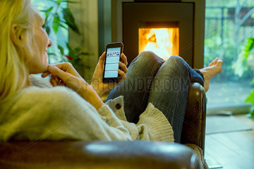 Mature woman relaxing at home with smartphone