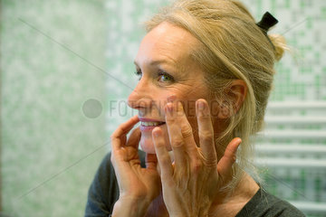 Mature woman scrutinizing face in mirror
