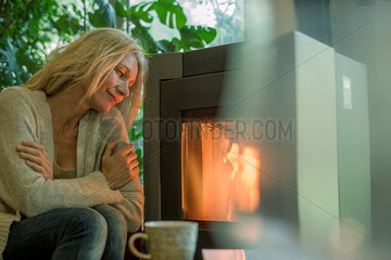 Mature woman relaxing by fireplace