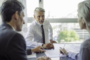 Woman signing document in meeting with business professionals