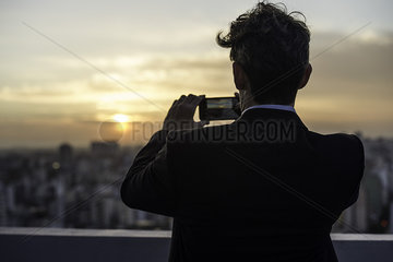 Man taking photograph of sunset
