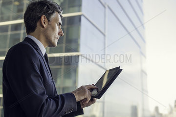 Man with digital tablet by window in high rise building