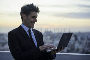 Businessman on rooftop using laptop
