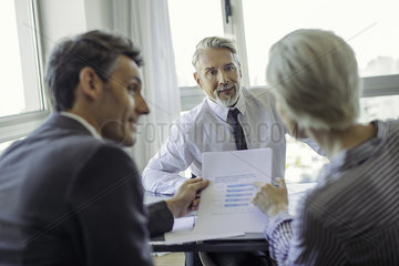 Couple reading document during meeting with businessman