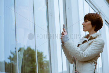 Woman photographing shop window with smartphone