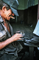 Cienfuegos  Kuba  Schuhputzer mit Zigarre bei der Arbeit