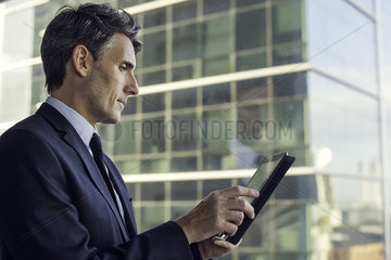 Man with digital tablet by window in high rise building