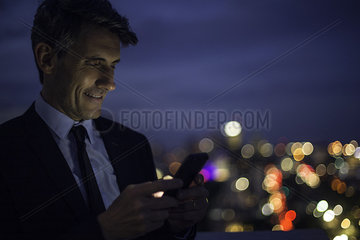 Businessman on high rise rooftop using mobile phone