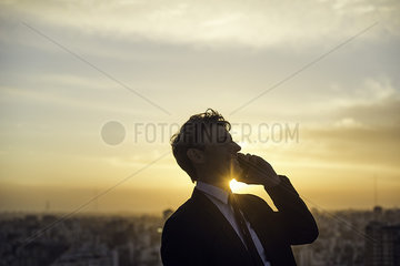 Man talking on cell phone back lit by setting sun