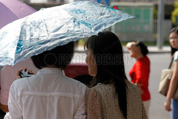 Shenzhen  China  zwei Frauen unterhalten sich unter einem Sonnenschirm