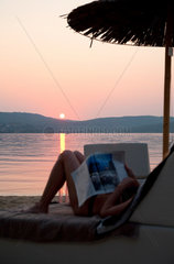 Vourvourou  Griechenland  eine Frau entspannt bei Sonnenuntergang am Strand