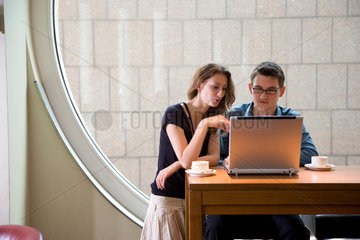 Freiburg  Deutschland  ein junges Paar sitzt mit einem Notebook in einem Cafe