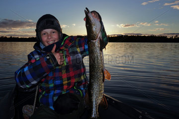 Lessebo  Schweden  Junge zeigt stolz seinen selbst geangelten Hecht auf dem See Rottnen