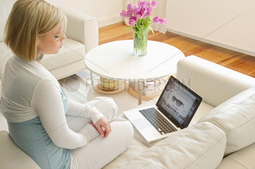 Hamburg  Deutschland  eine junge Frau mit einem MacBook im Wohnzimmer