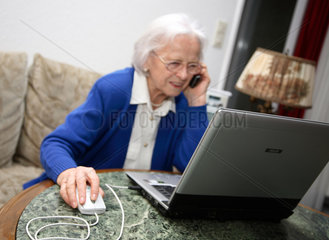 Berlin  Deutschland  eine alte Frau sitzt am Laptop und telefoniert