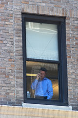 New York City  Mann telefoniert am Fenster