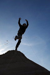 Schependorf  Deutschland  Silhouette  ein Junge springt von einem Sandhuegel