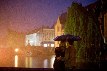 Bruegge  Belgien  ein junges Paar unter einem Regenschirm schaut auf eine Gracht