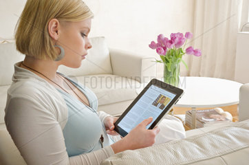 Hamburg  Deutschland  eine junge Frau sitzt mit ihrem iPad auf der Couch