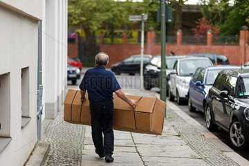Berlin  Deutschland  aelterer Mann schleppt ein grosses Paket