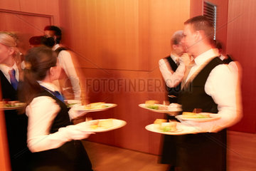 Berlin  Deutschland - Servicepersonal in vornehmer Garderobe beim Auftragen der Speisen bei einer festlichen Abendveranstaltung.