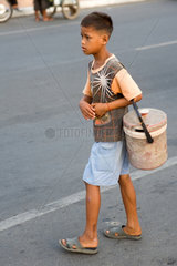 Phnom Penh  Kambodscha  ein Junge ueberquert eine Strasse mit einem Eimer im Arm
