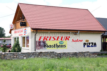 Osinow Dolny  Polen  Haus eines Friseursalons mit Werbung fuer Pizza und Gasthaus
