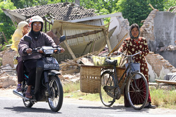 Bulus Kulon  Indonesien  Eine Frau schiebt ihr Fahrrad an Ruinen vorbei