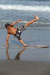 Cocoa Beach  USA  Junge faellt am Strand von seinem Surfbrett