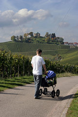 Stuttgart  Deutschland  Mann geht mit Baby im Kinderwagen spazieren