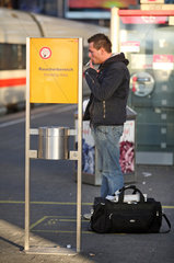 Muenchen  Deutschland  Mann raucht innerhalb des Raucherbereichs auf dem Bahnsteig