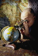 Hamburg  Deutschland  Mann schaut durch ein Fernglas auf ein Globus
