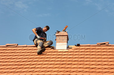Sosnowka  Polen  Dachdecker legt letzte Hand an ein frisch gedecktes Dach